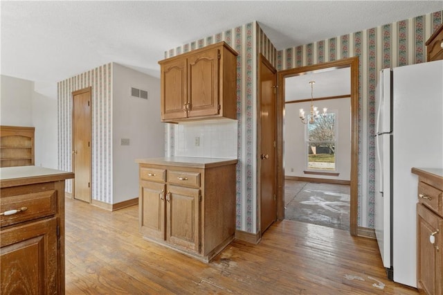 kitchen featuring wallpapered walls, baseboards, light wood-style flooring, freestanding refrigerator, and an inviting chandelier