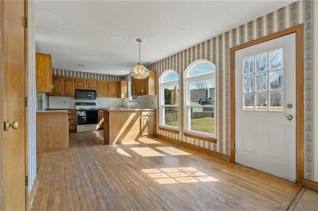 kitchen featuring wallpapered walls, electric range oven, light countertops, wood-type flooring, and black microwave