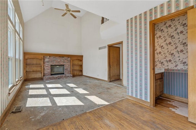 unfurnished living room with a wealth of natural light, visible vents, wood finished floors, and ceiling fan