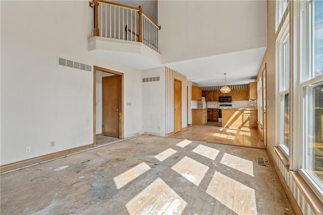 unfurnished living room with visible vents, baseboards, and a high ceiling