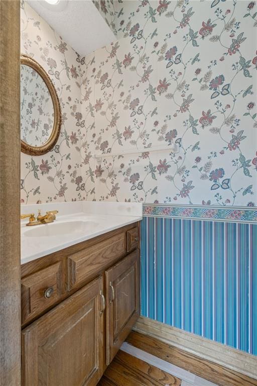 bathroom with wallpapered walls and vanity