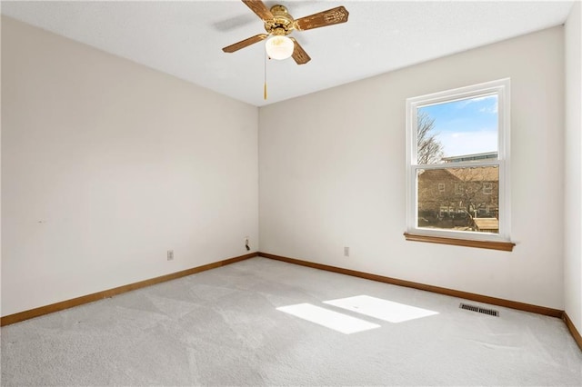 unfurnished room with ceiling fan, light colored carpet, visible vents, and baseboards