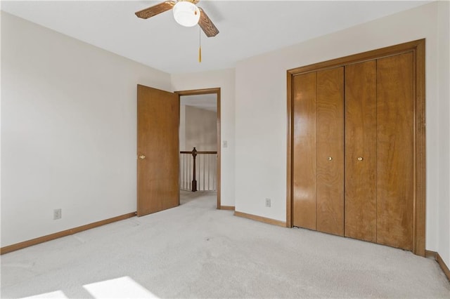 unfurnished bedroom featuring light colored carpet, baseboards, a closet, and ceiling fan