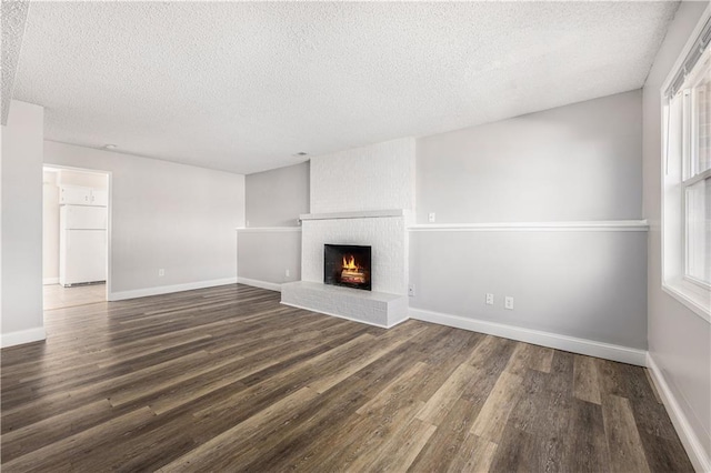 unfurnished living room featuring a brick fireplace, baseboards, and wood finished floors