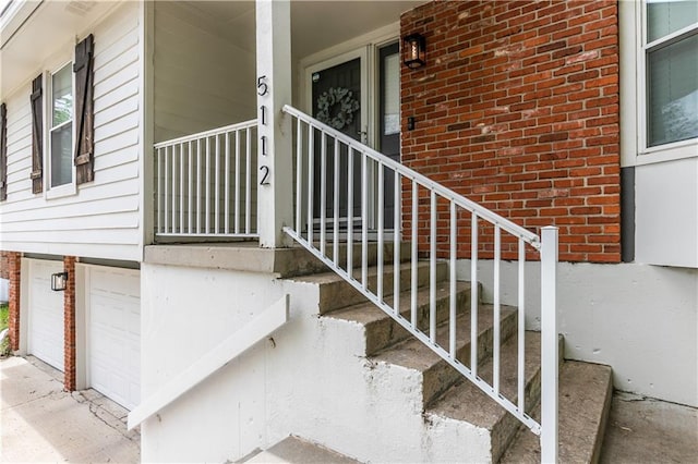 property entrance with a garage, a porch, and brick siding