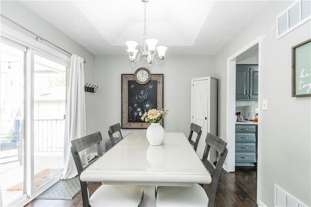 dining space with visible vents, a raised ceiling, dark wood-style floors, and an inviting chandelier