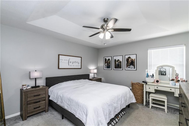 bedroom with a ceiling fan, baseboards, light colored carpet, and a raised ceiling