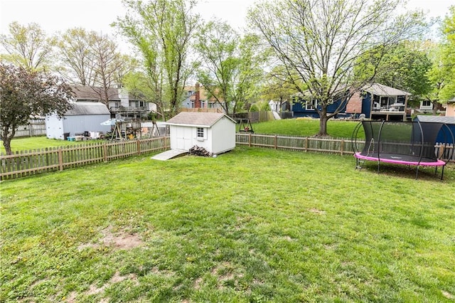 view of yard with a residential view, a trampoline, a shed, a fenced backyard, and an outbuilding