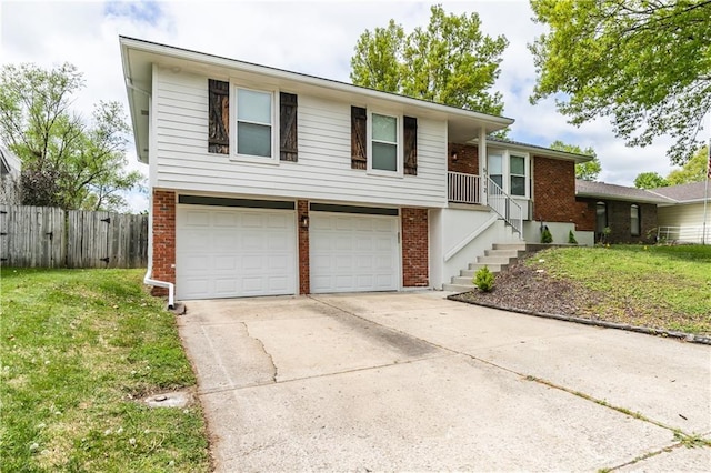 tri-level home featuring fence, brick siding, a garage, a front yard, and driveway