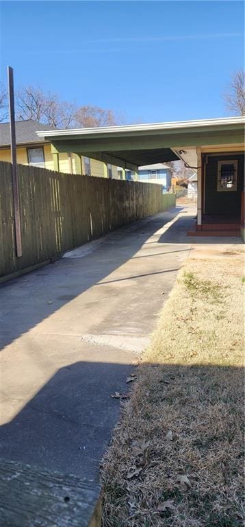 view of car parking featuring a carport, driveway, and fence