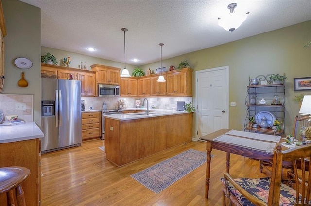 kitchen featuring a sink, light countertops, light wood finished floors, and stainless steel appliances