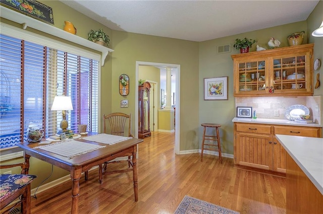 dining room featuring visible vents, baseboards, light wood-style floors, and decorative columns