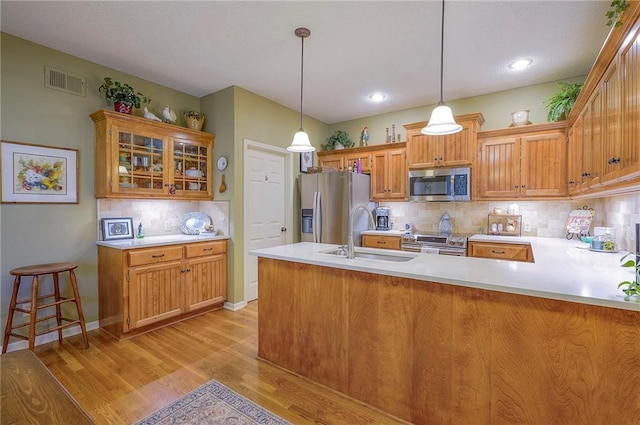 kitchen with light wood-type flooring, visible vents, a sink, stainless steel appliances, and light countertops