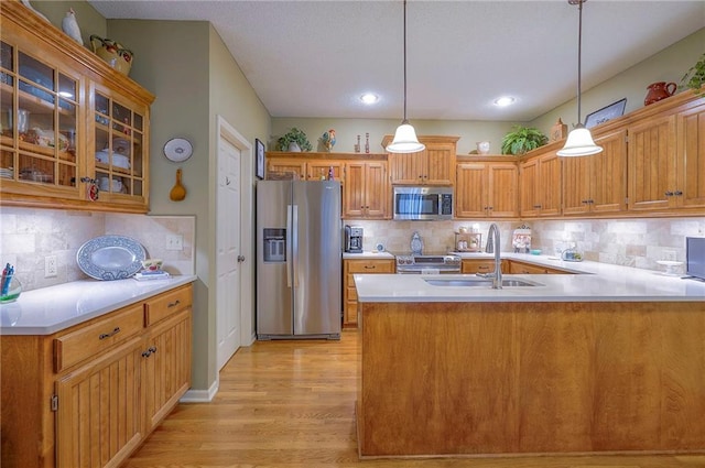 kitchen featuring pendant lighting, a sink, appliances with stainless steel finishes, a peninsula, and light wood finished floors