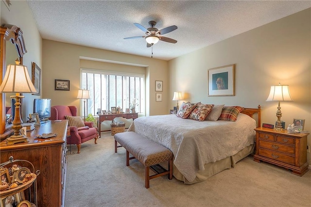 bedroom with a ceiling fan, light colored carpet, and a textured ceiling