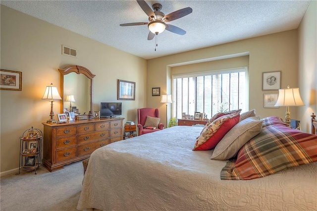 carpeted bedroom featuring baseboards, visible vents, a textured ceiling, and a ceiling fan