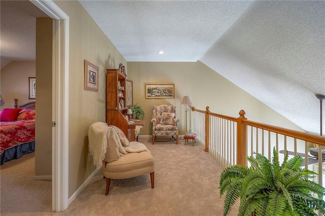 sitting room with baseboards, lofted ceiling, carpet, and a textured ceiling