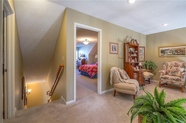 sitting room featuring baseboards, an upstairs landing, a textured ceiling, and carpet flooring