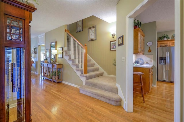 stairs featuring wood finished floors, baseboards, and a textured ceiling