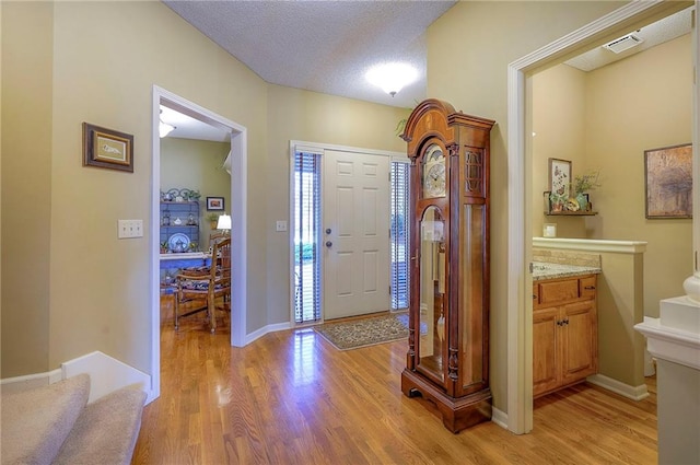 foyer entrance with stairs, light wood-style floors, visible vents, and a textured ceiling