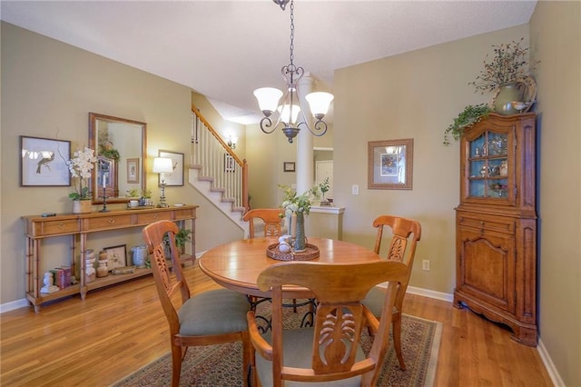 dining area with light wood finished floors, a notable chandelier, and baseboards