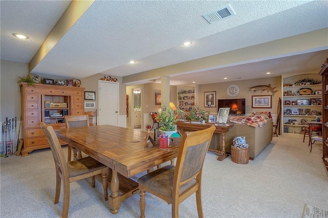 dining room with recessed lighting, light colored carpet, visible vents, and a textured ceiling