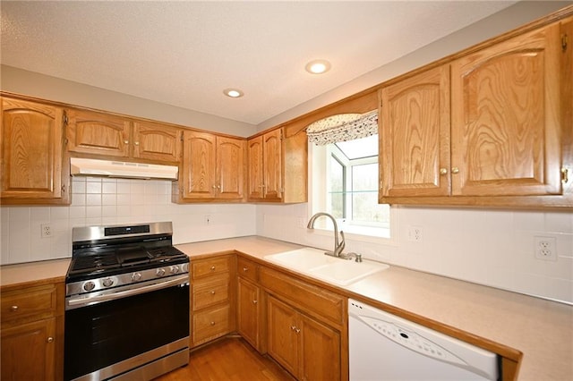 kitchen with stainless steel gas stove, under cabinet range hood, a sink, light countertops, and dishwasher