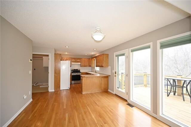 kitchen with visible vents, light wood-style flooring, stainless steel range, a sink, and freestanding refrigerator