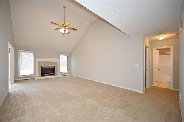 unfurnished living room with light carpet, high vaulted ceiling, a fireplace, baseboards, and ceiling fan