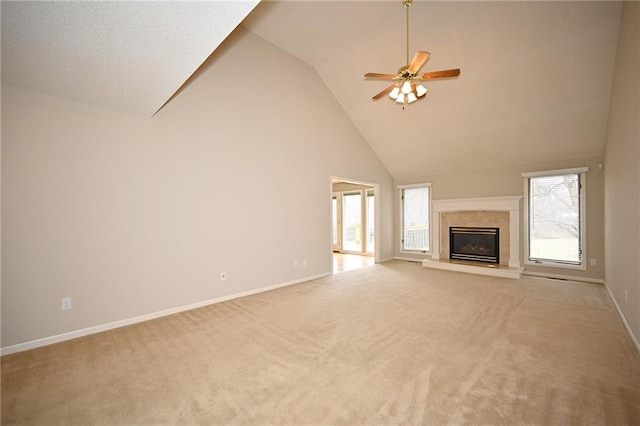 unfurnished living room featuring high vaulted ceiling, a high end fireplace, carpet, baseboards, and ceiling fan