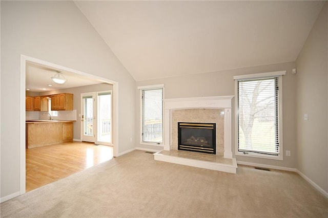 unfurnished living room with a fireplace, visible vents, a wealth of natural light, and a sink