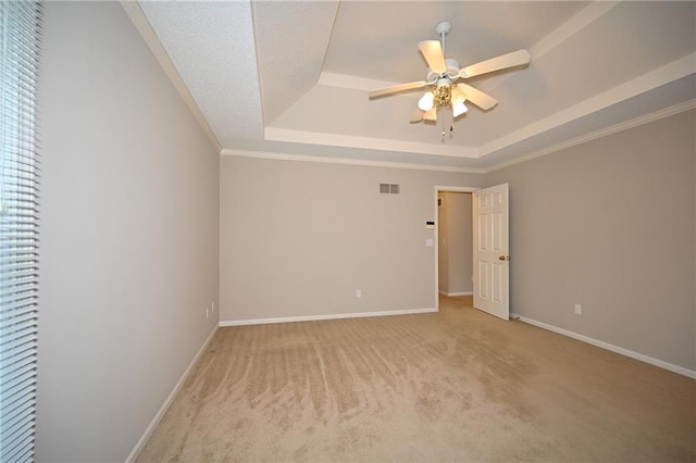 empty room featuring visible vents, a raised ceiling, baseboards, and a ceiling fan