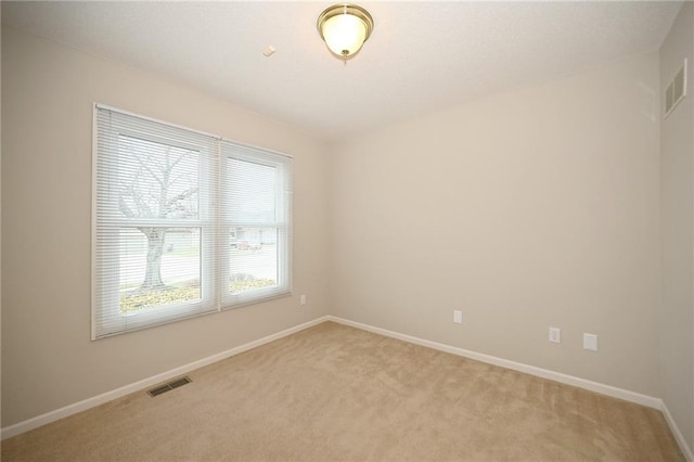 empty room featuring visible vents, baseboards, and light colored carpet