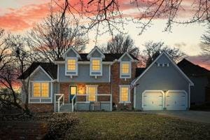 traditional-style house featuring a garage, a front lawn, and driveway