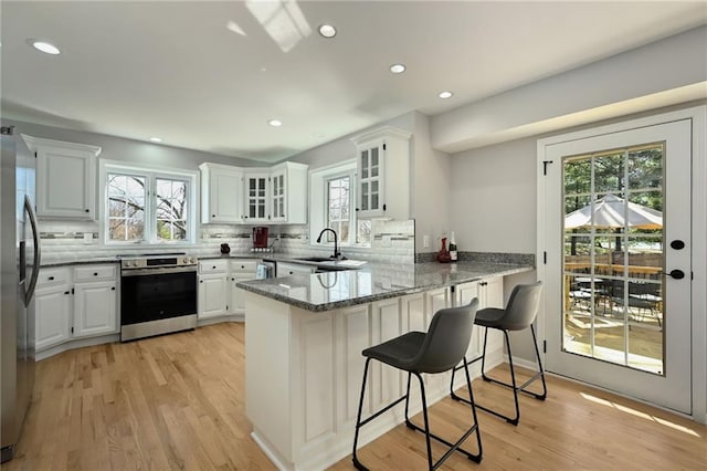 kitchen featuring tasteful backsplash, a peninsula, stone countertops, stainless steel appliances, and a sink