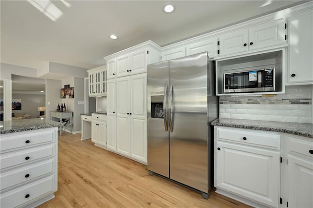 kitchen featuring dark stone countertops, tasteful backsplash, appliances with stainless steel finishes, and light wood-style flooring