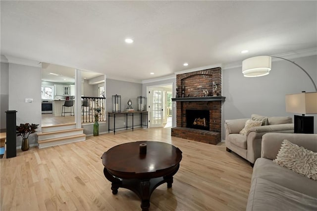 living area with a fireplace, crown molding, and wood finished floors