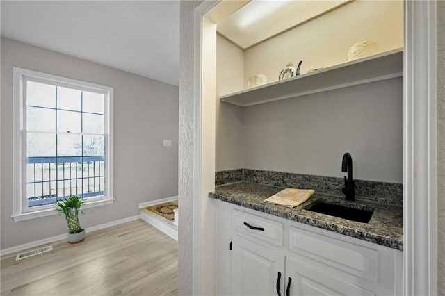 interior space with visible vents, baseboards, wood finished floors, and vanity