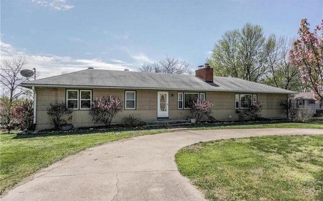 ranch-style house with a chimney and a front lawn