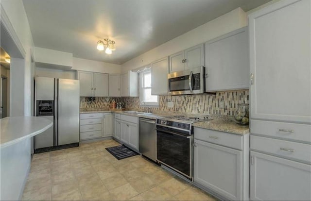 kitchen with tasteful backsplash, appliances with stainless steel finishes, light countertops, and a sink