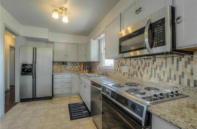 kitchen featuring tasteful backsplash, appliances with stainless steel finishes, light stone countertops, and a sink