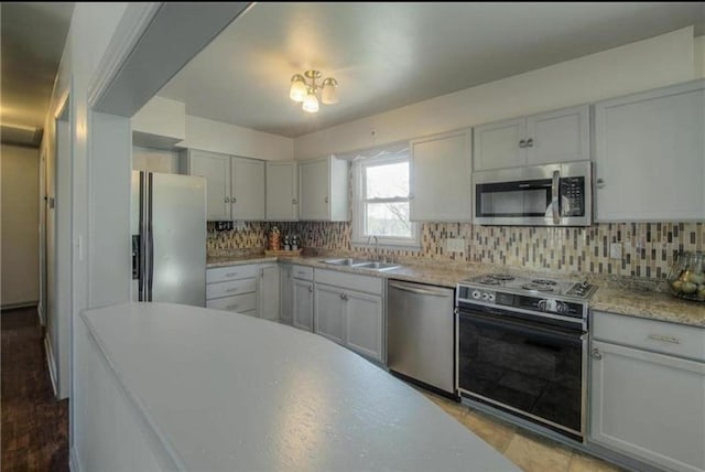 kitchen with a sink, decorative backsplash, light countertops, and stainless steel appliances