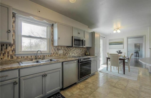 kitchen featuring a sink, gray cabinets, tasteful backsplash, and stainless steel appliances