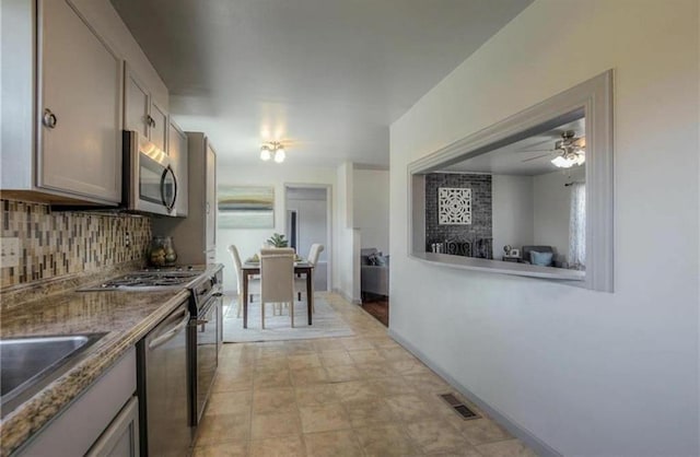 kitchen featuring visible vents, a sink, backsplash, appliances with stainless steel finishes, and baseboards