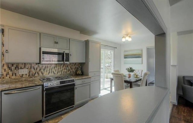 kitchen with gray cabinets, dark wood finished floors, appliances with stainless steel finishes, light countertops, and decorative backsplash