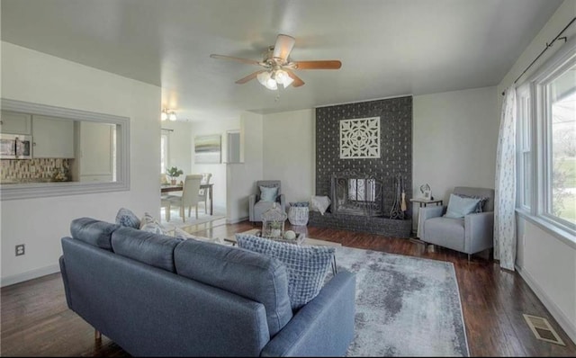 living area featuring visible vents, a fireplace, baseboards, and wood finished floors