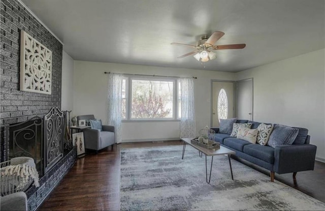 living room with a brick fireplace, baseboards, a ceiling fan, and wood finished floors