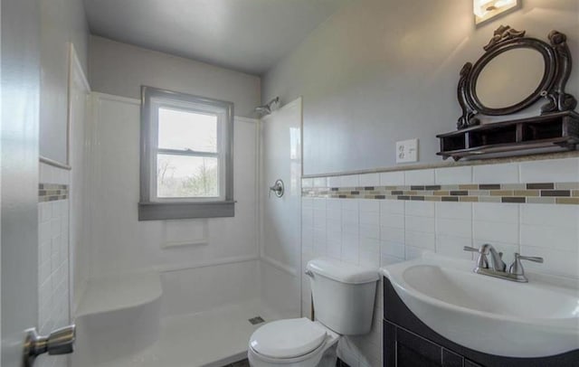 full bathroom featuring vanity, a shower, wainscoting, tile walls, and toilet