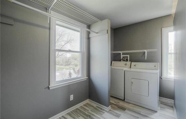 laundry room with laundry area, washing machine and dryer, baseboards, and light wood finished floors