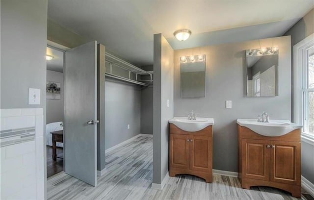 full bath featuring two vanities, a wealth of natural light, and a sink